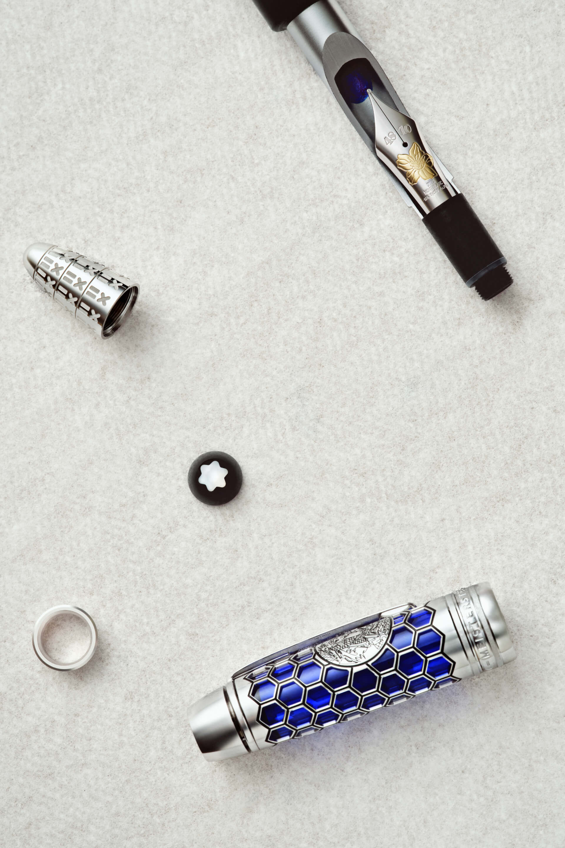Montblanc Meisterst&uuml;ck fountain pen, blue honeycomb dragon cap, gold nib, snowcap emblem, disassembled on light surface.