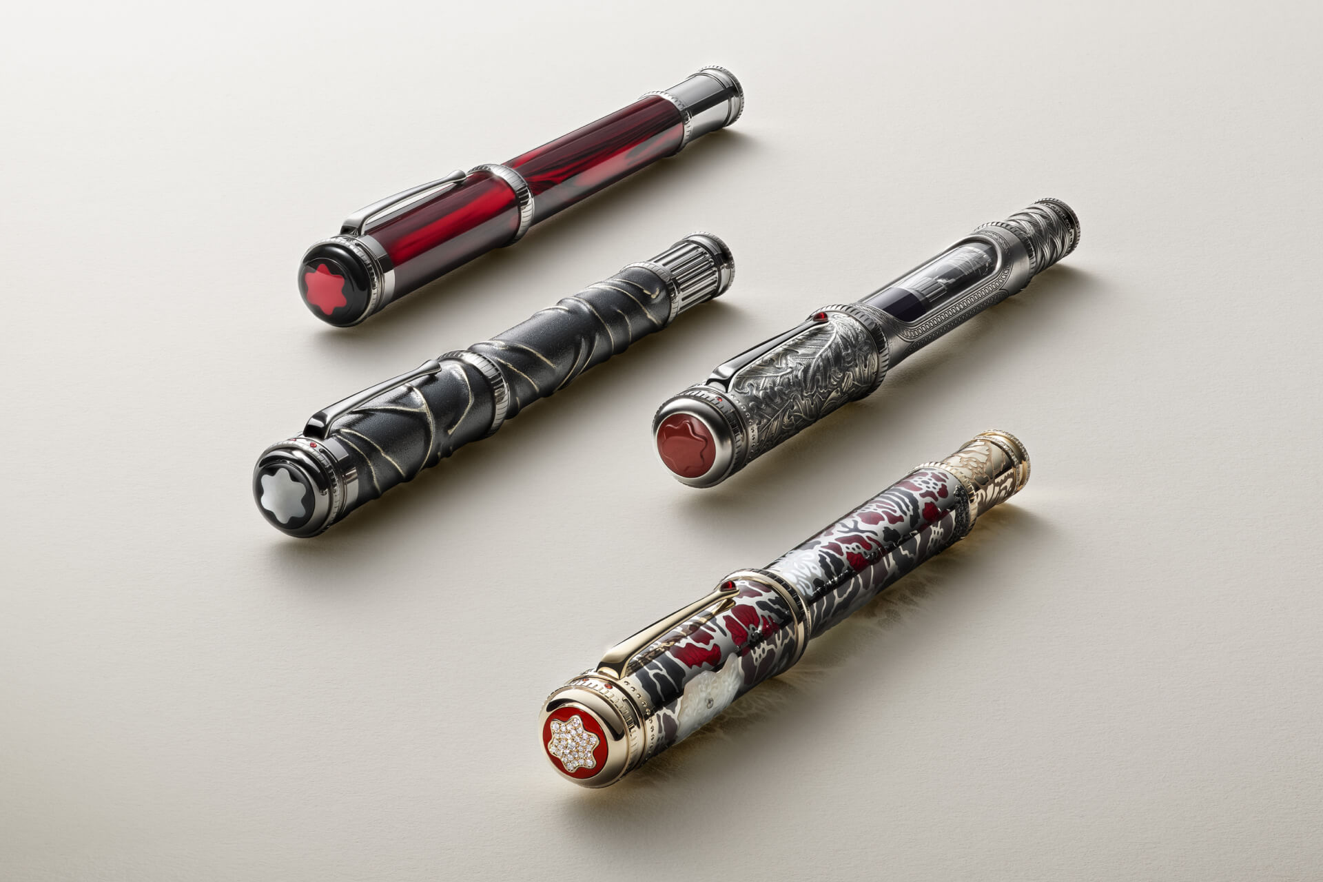 Montblanc luxury fountain pens, a collection with diverse designs including engraved metal and a patterned pen with a diamond snowcap emblem, on a light background.