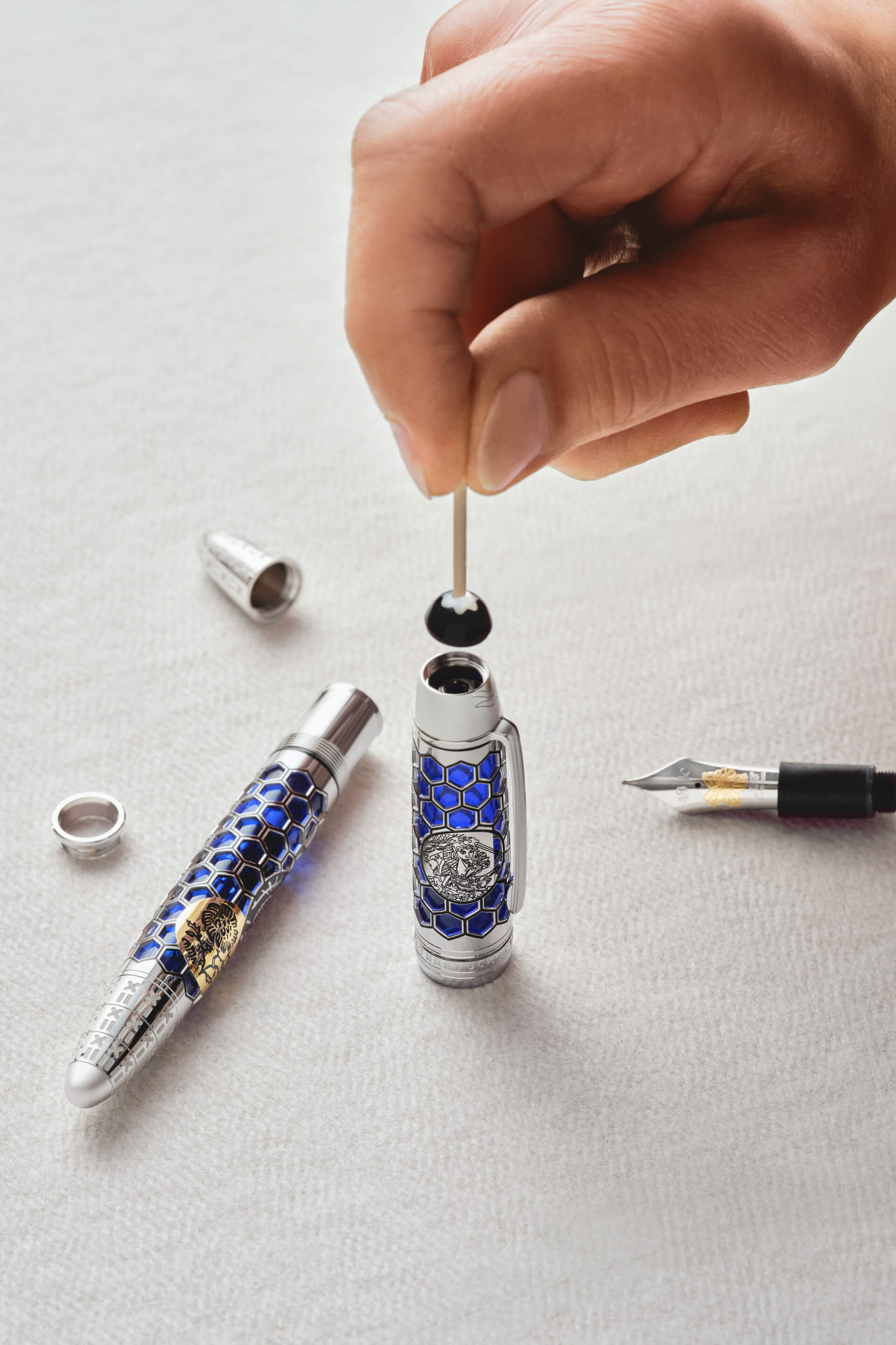 Montblanc fountain pen, silver-toned with blue hexagonal pattern and engraved mythical creature, nib and filling mechanism displayed.