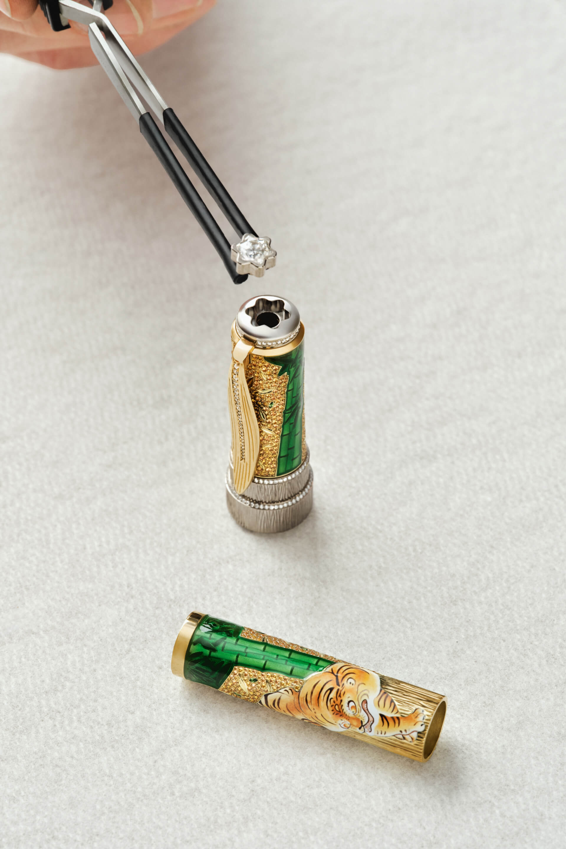 Montblanc luxury writing instrument cap, detailed with green enamel bamboo, gold gemstones, and diamond pav&eacute;, as the star emblem is placed.