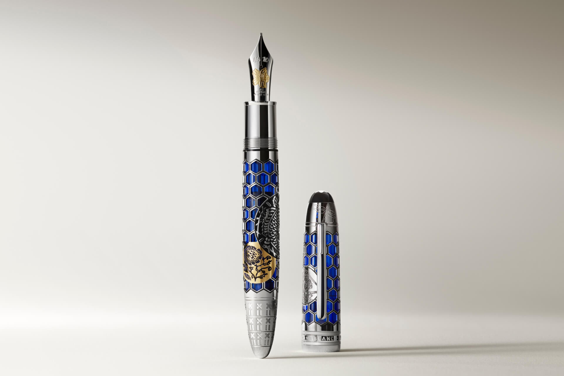 Montblanc fountain pen, silver-toned with blue hexagonal pattern, gold-accented emblem, and intricate two-tone nib, uncapped on a white background.