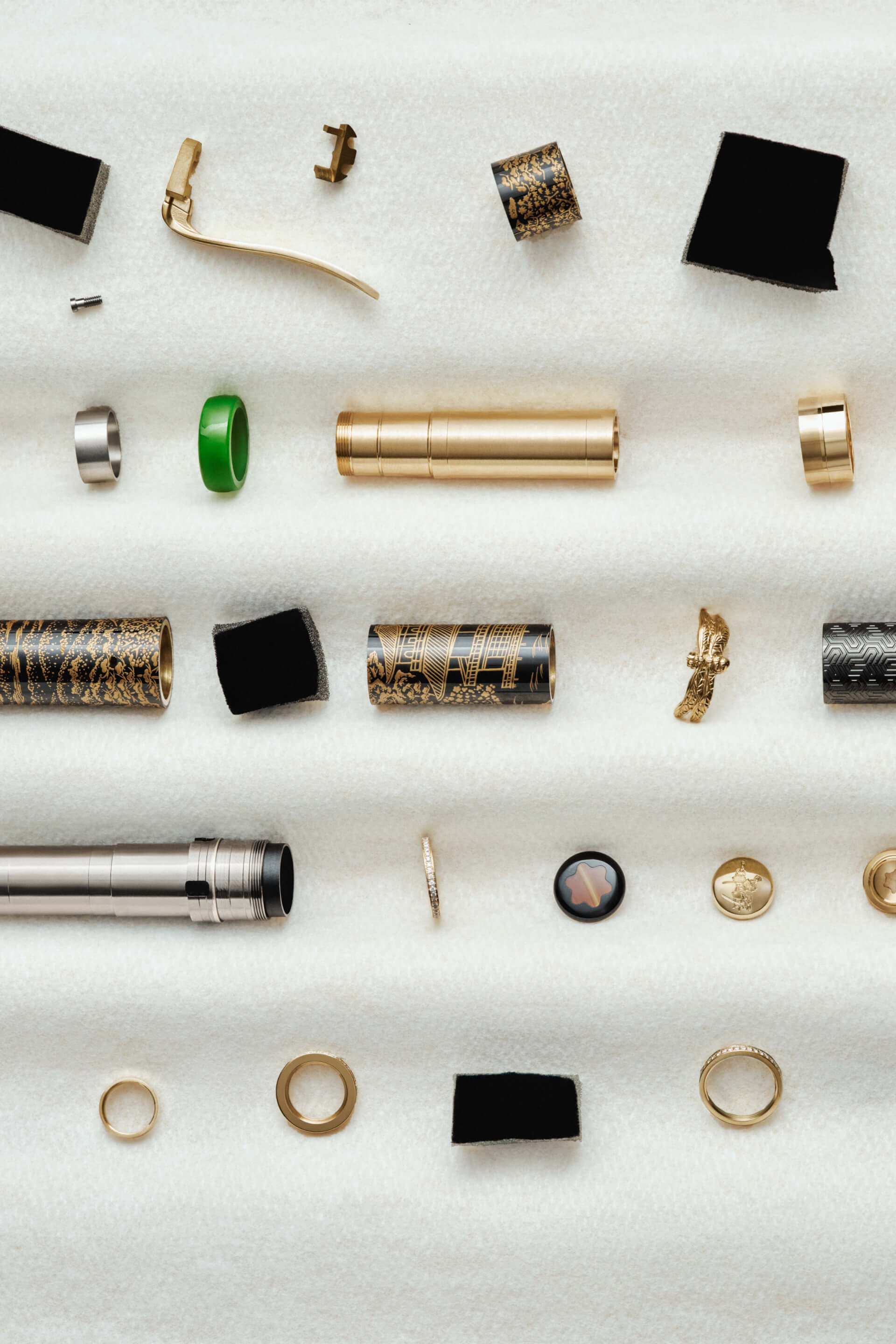 Montblanc special edition writing instrument components, including a black lacquer barrel with intricate gold Japanese art, polished gold and silver metal elements, and a Montblanc emblem, displayed disassembled on a plush white surface.