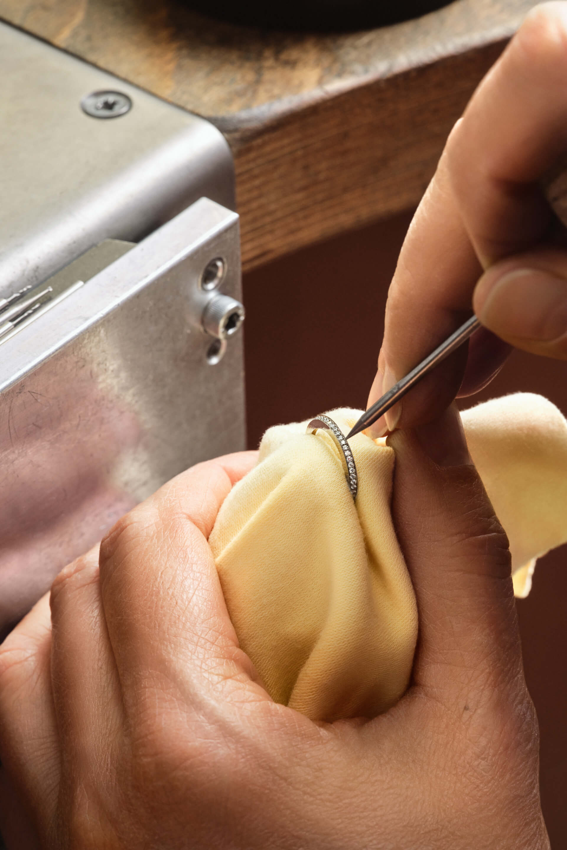 Montblanc diamond ring, gold-toned, intricately set with brilliant diamonds, being meticulously adjusted by a craftsman's hand with tweezers.