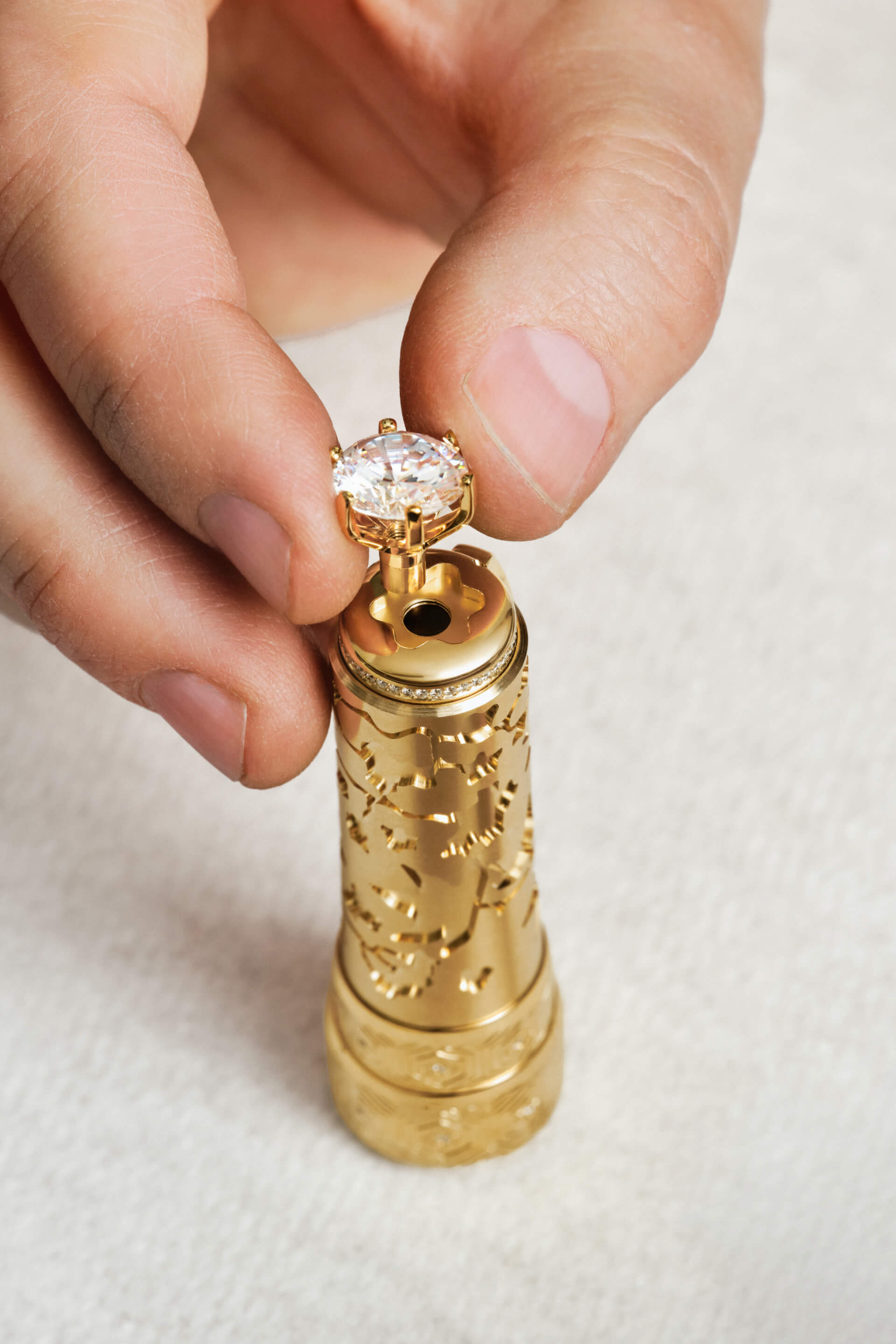 Montblanc luxury fountain pen, close-up of a hand precisely setting a brilliant-cut diamond finial into an intricately engraved gold barrel with pav&eacute; diamonds.